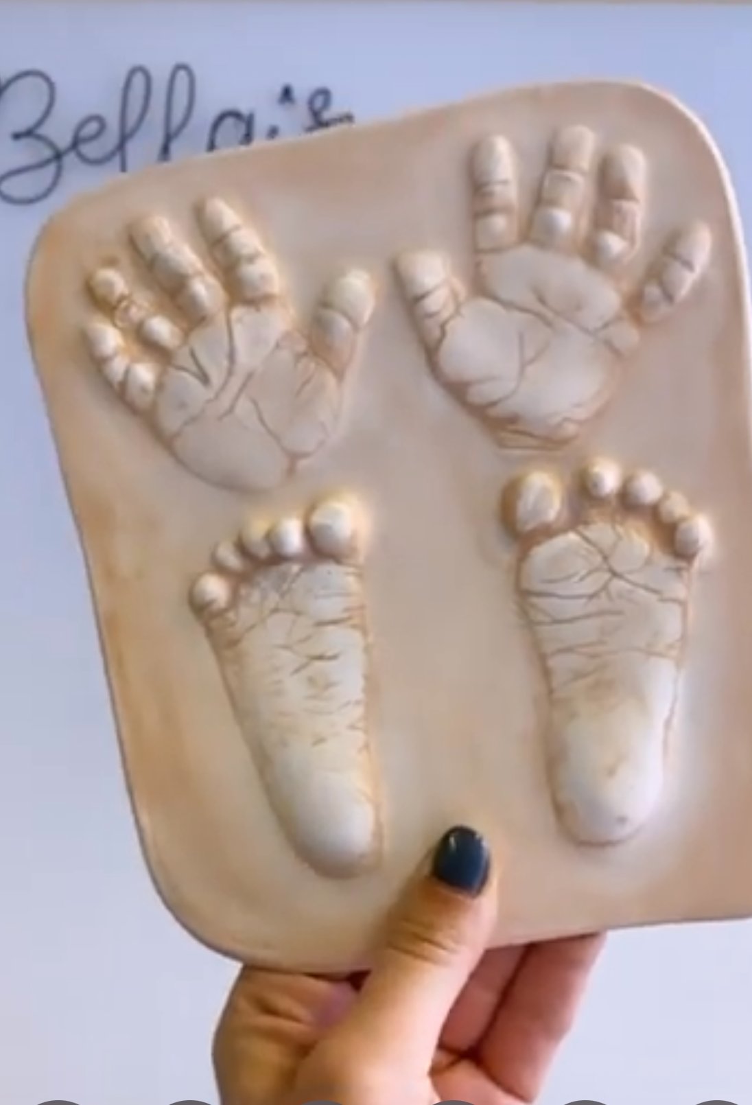 Raised 3D ceramic cast of a baby's hands and feet, held in one hand