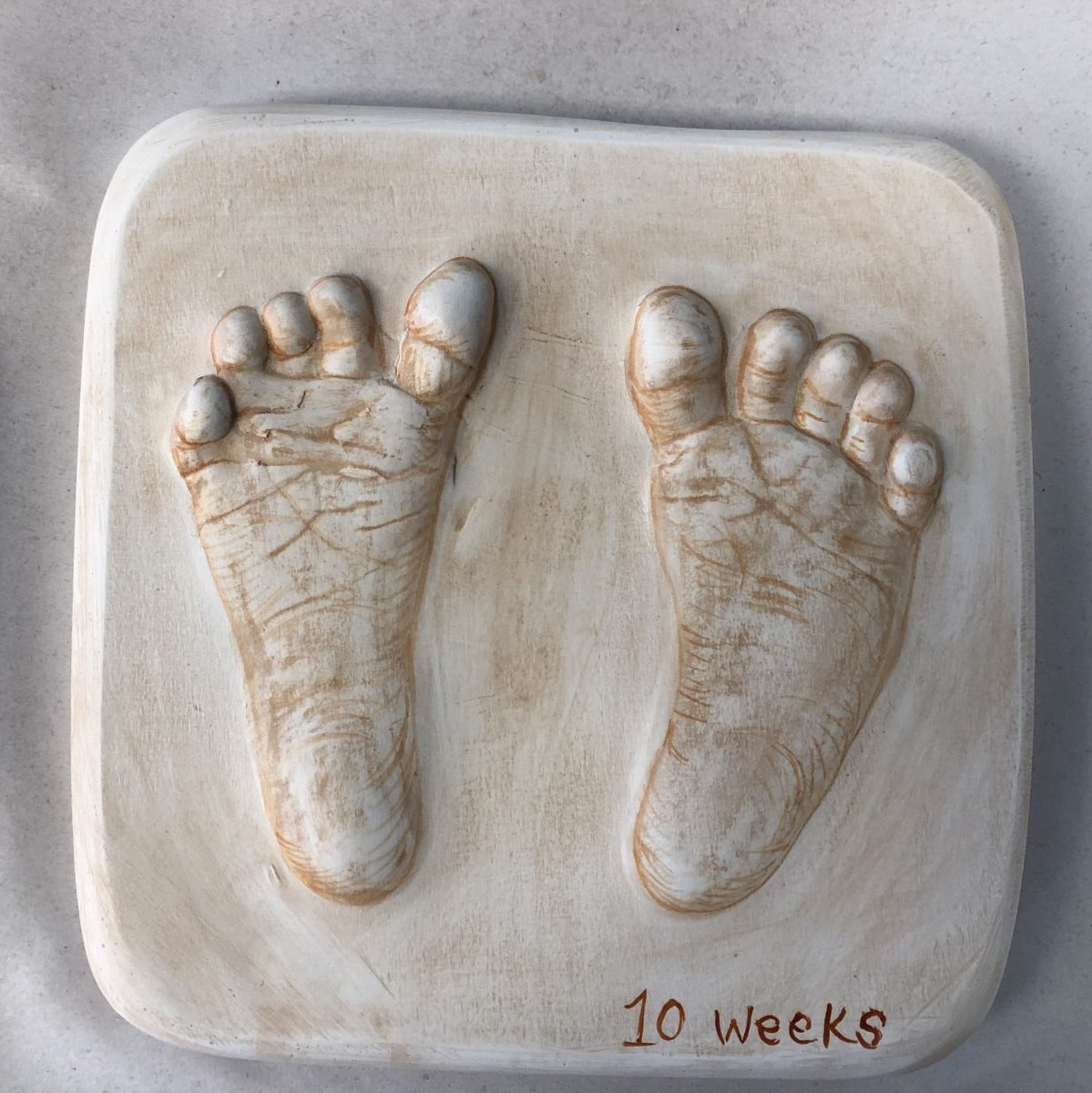 Raised ceramic cast of two baby feet, soft glazed