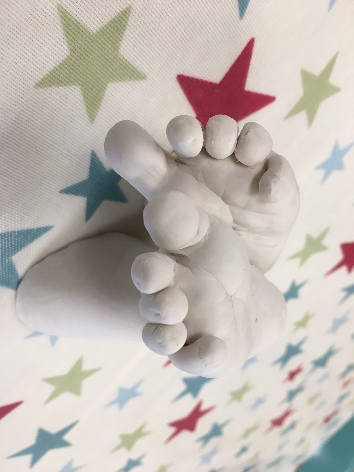 White cast of crossed baby feet on star fabric