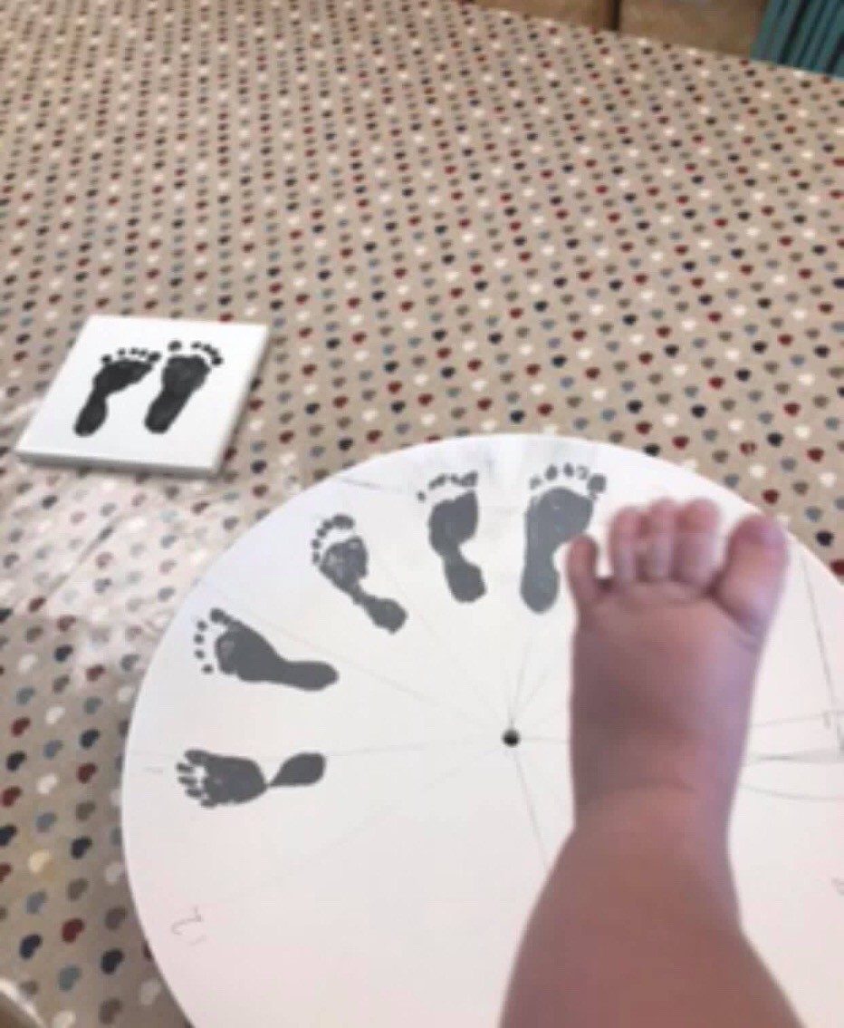 A baby foot printing the hours onto a clock face