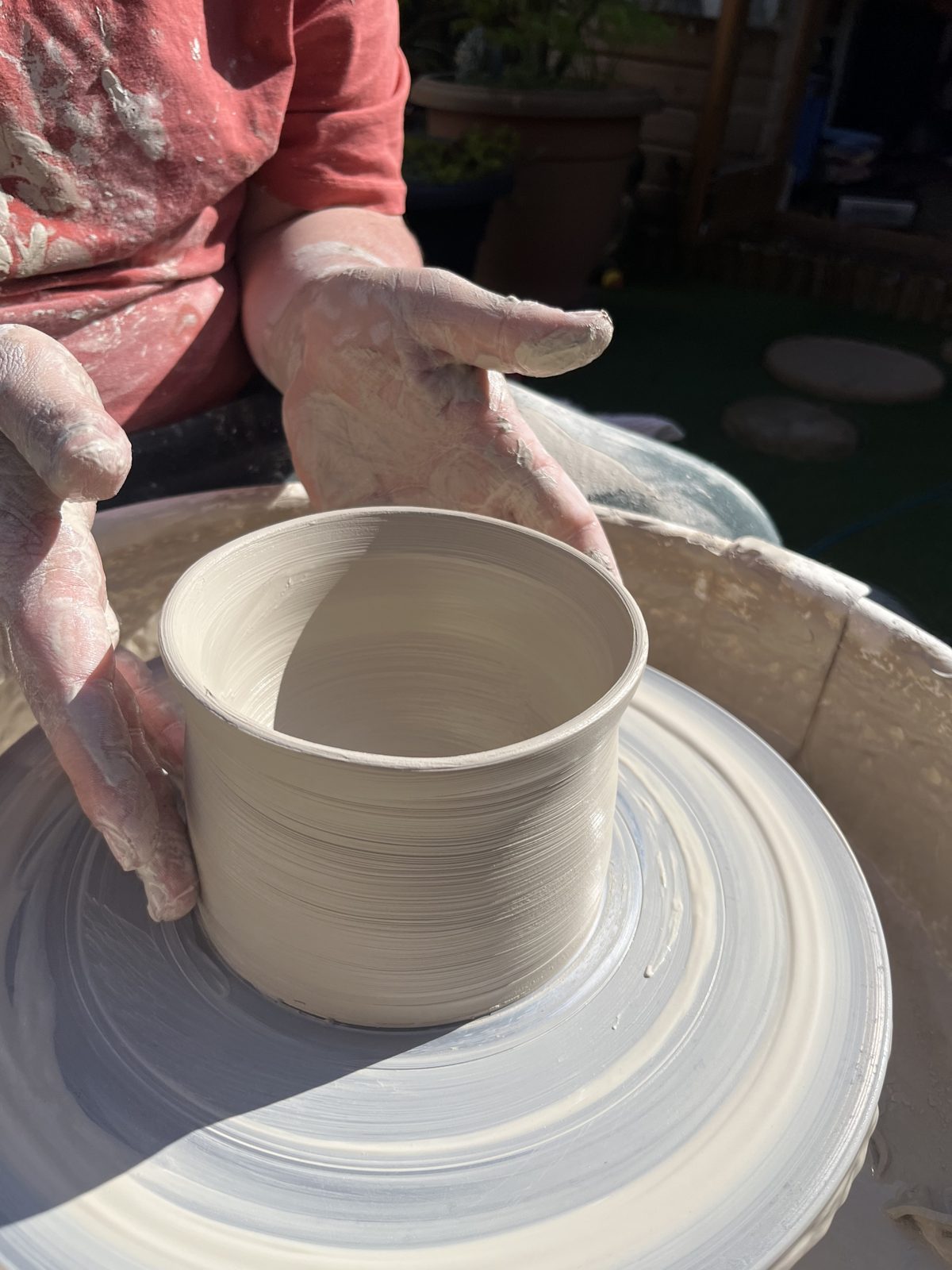 Hands shaping a pot on the wheel